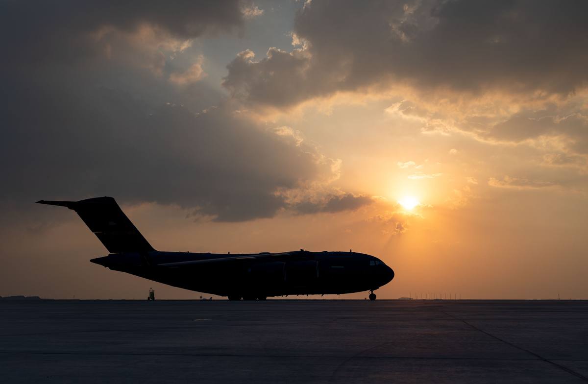 A C-17 aircraft silhouetted on the flight line at sunset